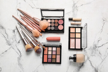 Makeup brushes and cosmetics on light background