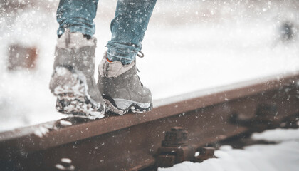 girl in boots walking on rails in winter