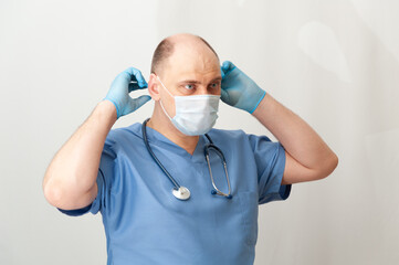 A doctor with a stethoscope, wearing a mask and gloves. A medical professional.