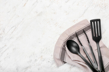 Set of kitchen utensils and napkin on light background