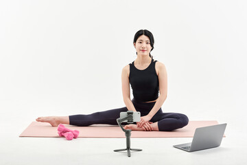 Obraz premium Asia Korean Girl training at white background , watching videos on laptop, and live streaming using gimbal in sns