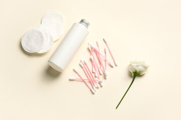 Bottle of cosmetic product, cotton swabs and pads on light background