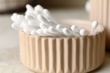 Fototapeta na wymiar Bowl with cotton swabs on light background, closeup