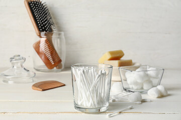 Glass with cotton swabs and bath supplies on table in bathroom