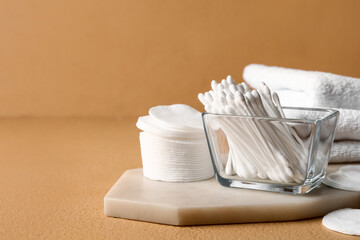 Bowl with cotton swabs, pads and towels on color background