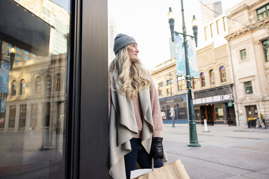 Thoughtful blonde woman shopping in city in winter