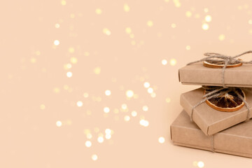 Pile of gift boxes on a beige background with glowing gold bokeh. Holidays preparation composition with place for your design.