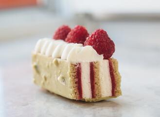 Appetizing pistachio dessert with raspberries in section. Slice of delicious dessert. Close up of mousse cakes. Euro dessert