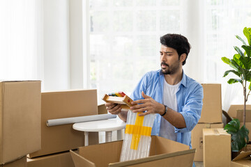 Adult man with mustache and beard packaging cardboard boxes for moving into a new house