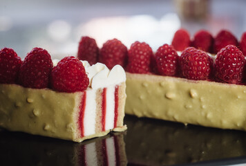 Appetizing pistachio dessert with raspberries in section. Slice of delicious dessert. Close up of mousse cakes. Euro dessert