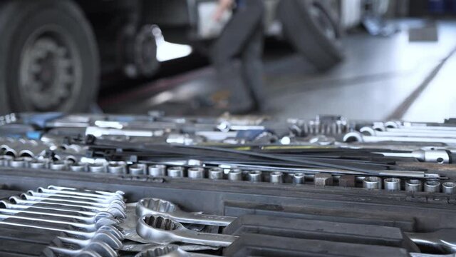 POV on set with professional tools. A mechanic with a tool in his hands goes to the cargo trailer and begins to repair it. Annual maintenance at a truck service station