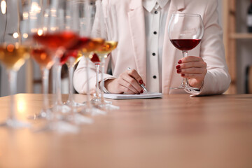 Sommelier tasting different sorts of wine at table indoors, closeup