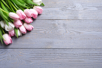 Beautiful pink spring tulips on grey wooden background, flat lay. Space for text