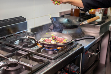 Cuisson de bœuf et de légumes dans une poêle dans un restaurant asiatique