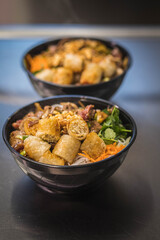 Salade de Nems avec des path thaïlandaise dans un bol noir dans un restaurant asiatique
