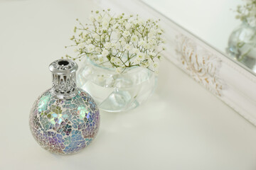 Stylish catalytic lamp with beautiful gypsophila on white table, space for text. Cozy interior