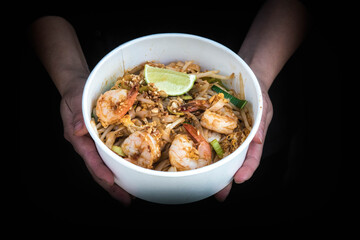Plats vietnamien et thaïlandais dans les mains d'une femme sur fond noir