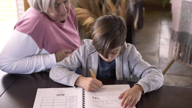 Grandmother helping grandson with homework at table