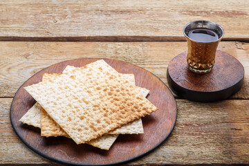 On a wooden table matzah and a glass of wine for kiddush on a round board.