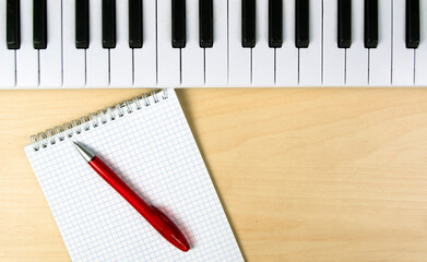 Workplace of a composer or singer. Synthesizer keyboard, notepad and pen. Place for text