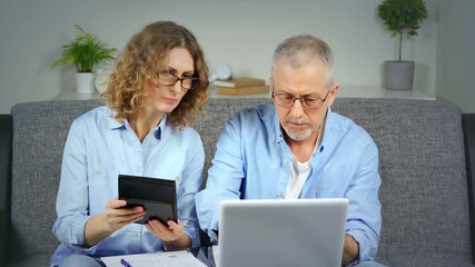 A married couple discusses financial expenses on a laptop.