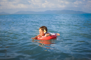 adorable toddler toddler swim in the sea in a special inflatable life ring.