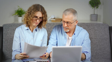 A married couple discusses financial expenses on a laptop.