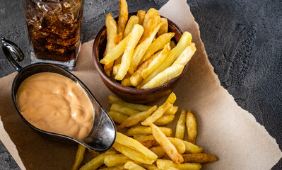 Close up view of delicious french fries with sauce and ice glass
