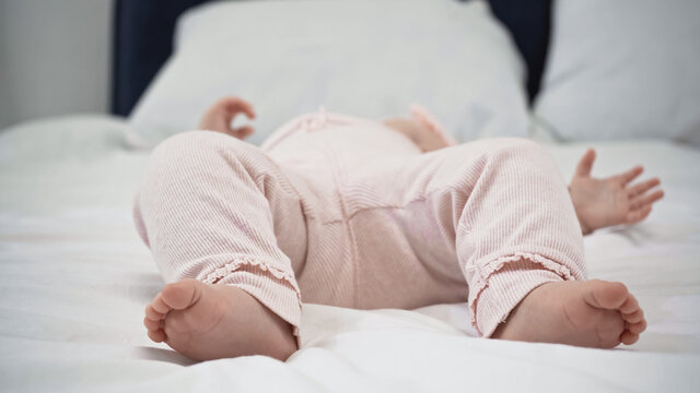 cropped view of baby with barefoot resting on bed.