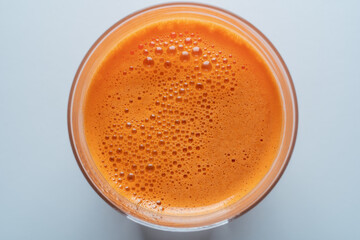 Glass of fresh carrot juice background, top view, close up