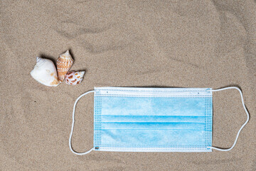 Seashells and medical mask, top view, there is a place for text. Summer vacation concept by the sea