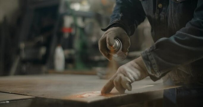 Locksmith paints metal detail with spray can in slow motion, painting at workshop with stencil, spray painting at the garage, 4k 60p Prores HQ