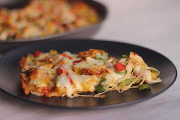 A thin crust homemade pizza loaded with cheese, chicken and vegetables.