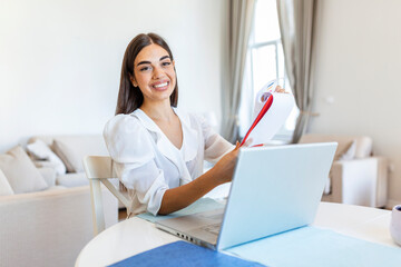 Smiling young woman study at home with laptop,online research for coursework, online education...