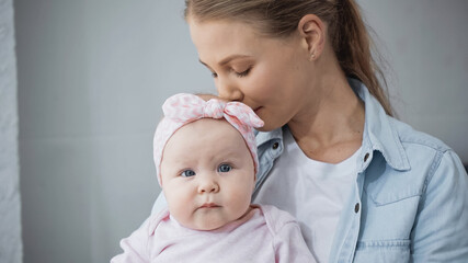 young mother smelling hair of infant daughter.