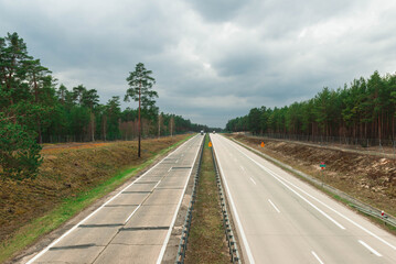 Autostrada przebiegająca przez sosnowy las. - obrazy, fototapety, plakaty