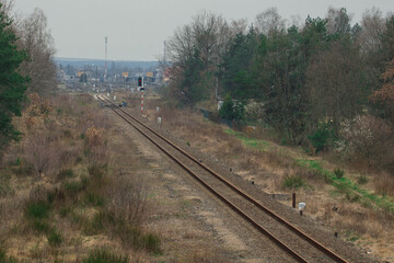 Tory kolejowe prowadzące w kierunku odległej stacji kolejowej.