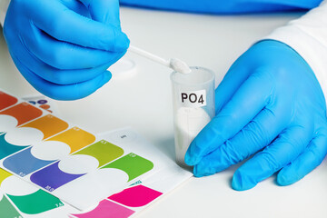 laboratory assistant in medical gloves holds a reagent for testing aquarium water in his hands, close-up