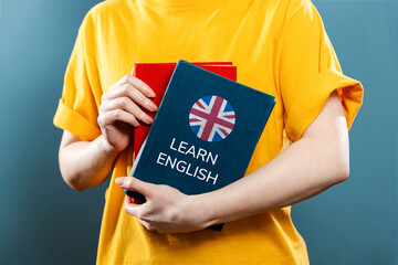 English Language Day. A woman holds English textbooks in her hands. Close-up of books. Blue...