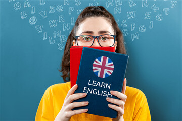 English language day. Portrait of a young woman holding english dictionary, covering half of her...