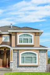 A perfect neighborhood. Houses in suburb at Summer in the north America. Fragment of a luxury house with nice window over blue sky.
