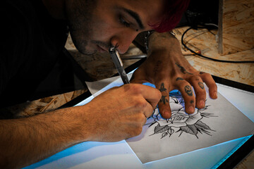 Obraz premium A tattoo artist sketching a tattoo in his tattoo studio.