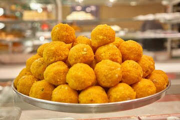 A laddu is a traditional Indian dessert in a spherical shape. Piled up here. Interior photo. Normal perspective. It is also served at weddings. 