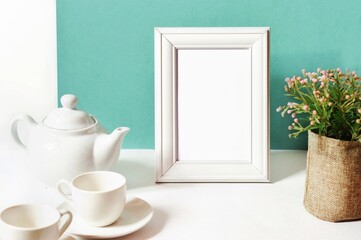 Porcelain teapot, coffee cups, photo frame or painting on the table. Modern kitchen interior in aquamarine