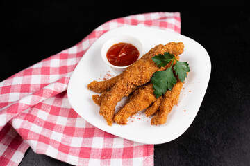 fried chicken wings nuggets with ketchup on black background
