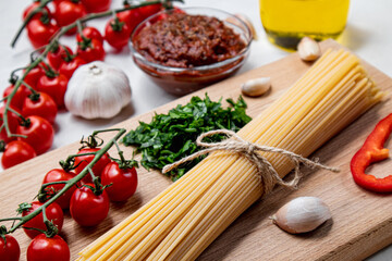 Spaghetti with tomatoes on a kitchen board on a white plate.
