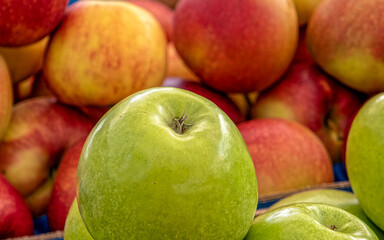 a green apple on red apple's background, fresh vegetarian food