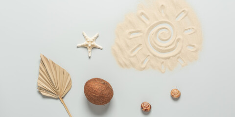 Fototapeta na wymiar Summer beach composition. Drawing of the sun on the sand, coconut, starfish, seashells and dry palm leaf on a gray background. Top view, flat lay. Creative layout. Banner