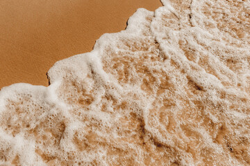 Areia e água do mar com onda batendo