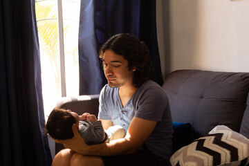 young happy hispanic father hugging and holding his newborn baby